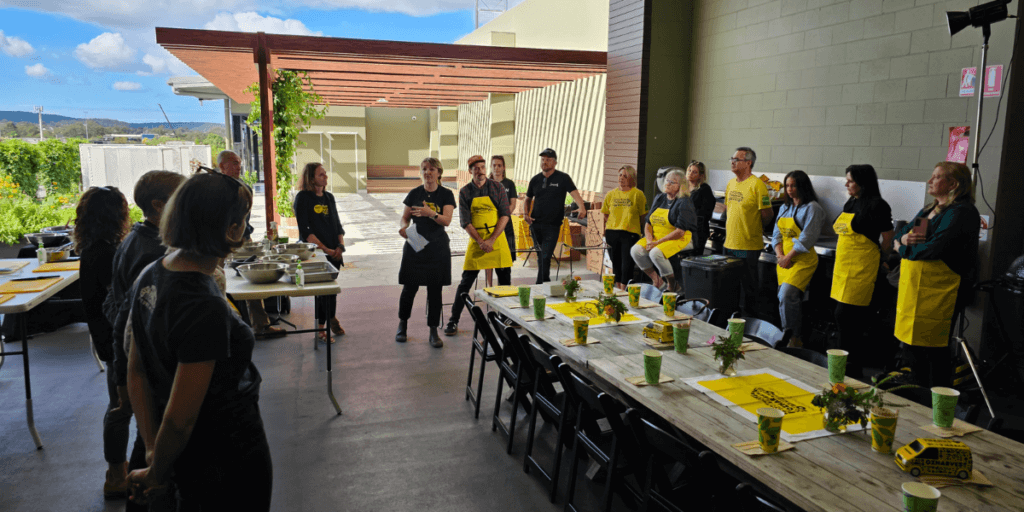 Event participants listening to speakers in an outdoor space next to a kitchen.